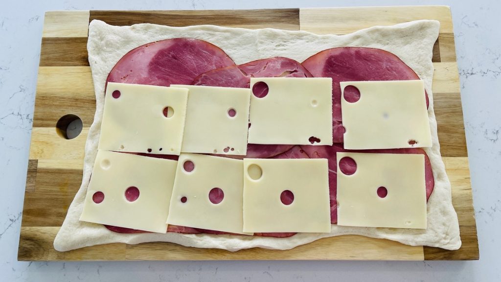 Cover the ham with Swiss cheese.